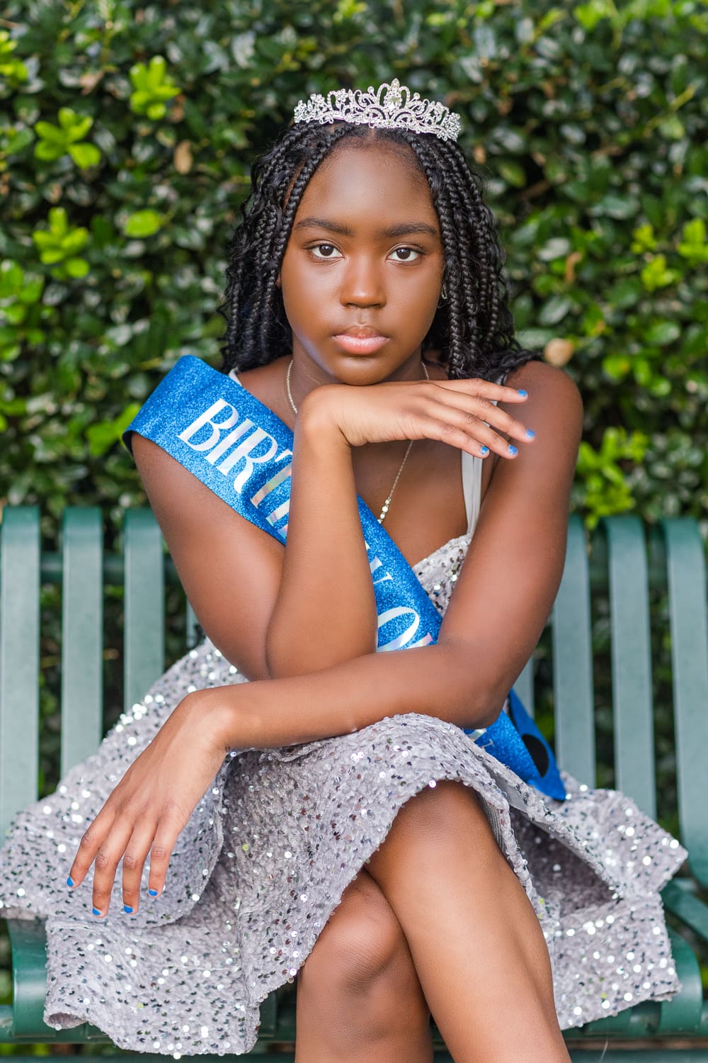 Close-up portrait of Aris wearing a tiara and blue Birthday Queen sash for her 13th birthday photo session.