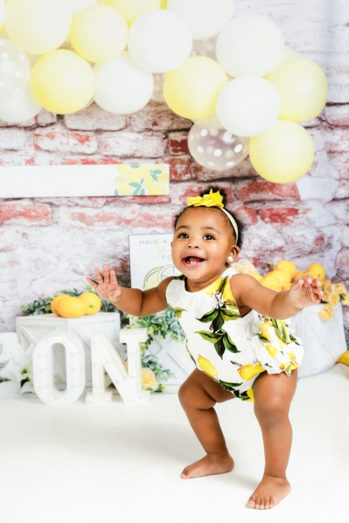 one year old girl smiling big during her lemon themed birthday session