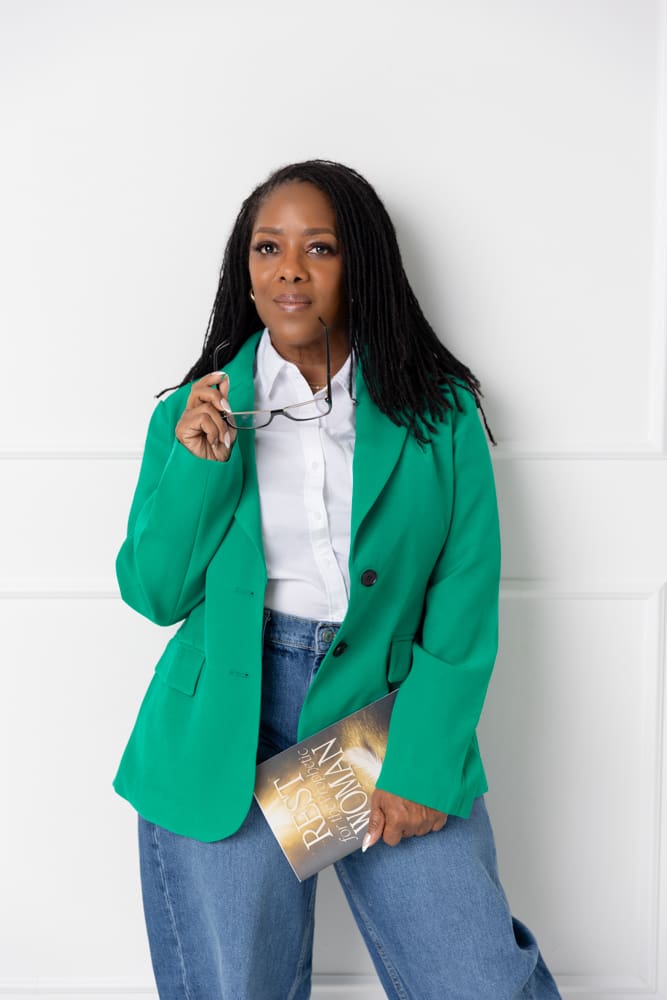 Professional branding portrait of a woman wearing a green blazer and holding a book against a white background.